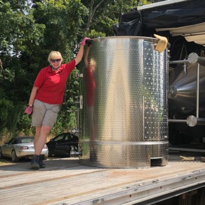 Maggie standind with wine tank